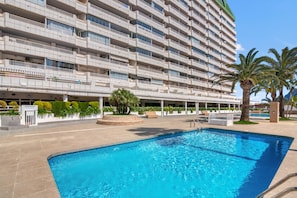 A hotel with a swimming pool, multiple balconies, and palm trees. - Apartment 'Vistas Al Mar A' with Sea View, Wi-Fi and Air Conditioning (Calp)