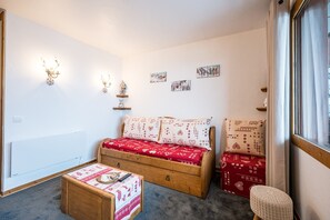 Una habitación acogedora con cama, una mesita, una silla y luces en la pared.