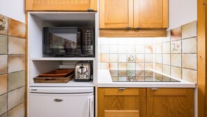 Kompakti keittiö, jossa on mikroaaltouuni, leivänpaahdin ja jääkaappi.