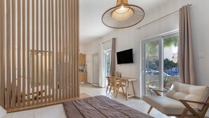 Quarto moderno com cama grande, divisória de madeira, área de refeições e TV.
