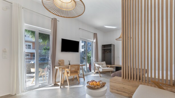 Uma sala de estar moderna com televisão de tela plana, área de jantar com cadeiras de madeira, sofá branco e divisória de madeira.