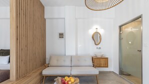 Uma sala de estar moderna com um sofá, um divisória de madeira, uma tigela de frutas, um espelho e uma porta de vidro.
