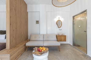 A modern living room with a sofa, a wooden partition, a fruit bowl, a mirror, and a glass door.