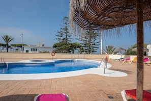 En swimmingpool med liggestole, en livreddersstol og frit udsyn til det omkringliggende landskab.