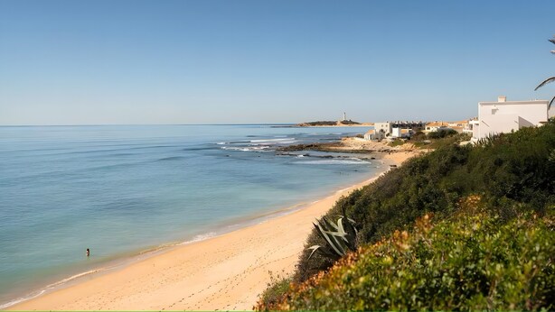 A coastal beach with a clear sky, a sandy shore, and buildings in the background. - Apartment 'En Los Caños De Meca' with Sea View, Wi-Fi and Air Conditioning (Los Caños de Meca)