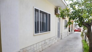 Un sendero estrecho que conduce a un edificio con ventanas amplias y base de baldosas.