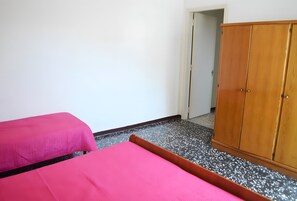 A room with two beds, a wooden wardrobe, and a door leading to another room. - Holiday Home 'Casa A T Dell Orso X 6 Guests' with Private Garden (Torre dell'Orso)
