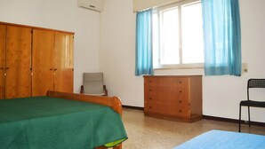 Una habitación con cama, armario de madera, escritorio y silla.