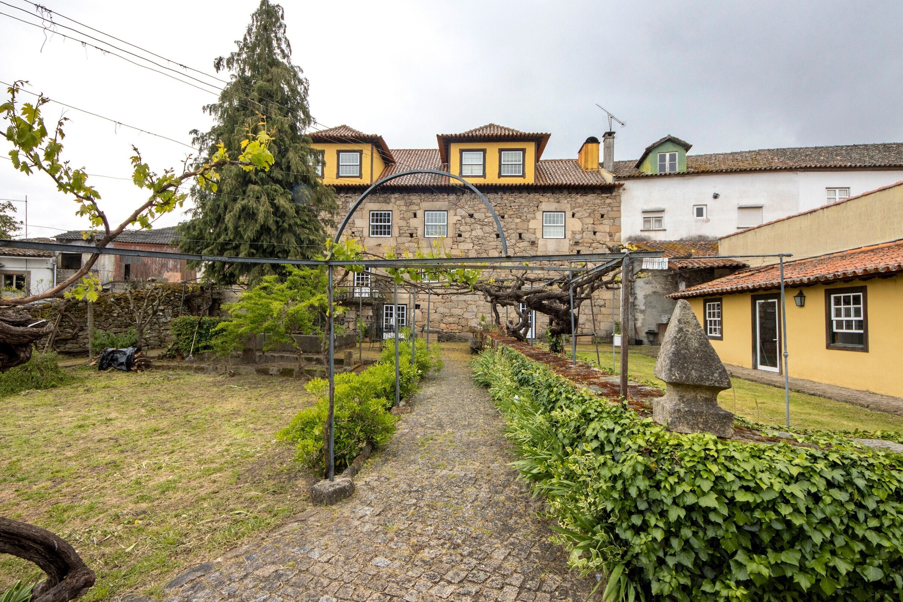 Un patio con sendero de piedra, una pérgola y una escultura de piedra.