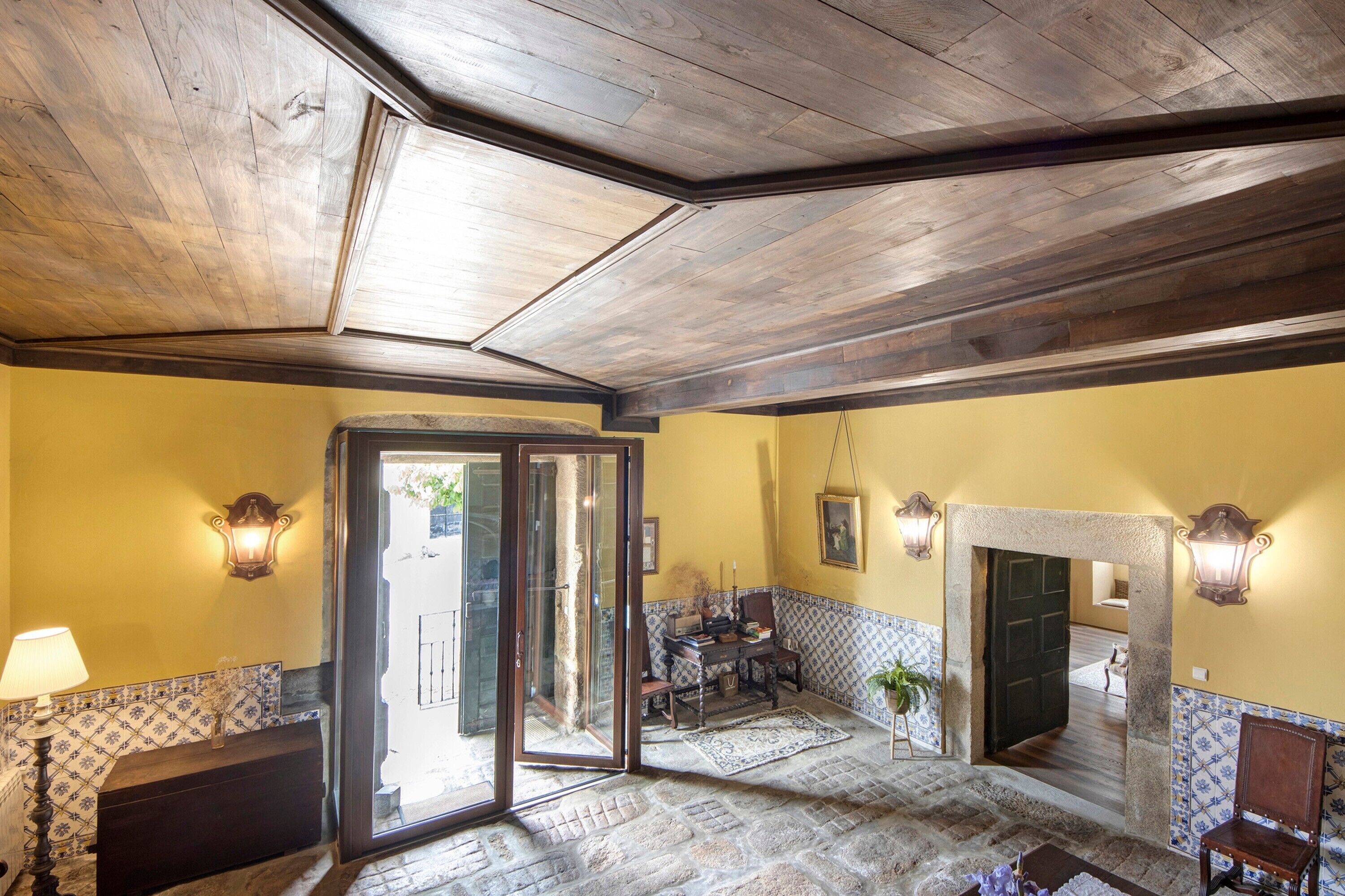Habitación con techo de madera, suelo de piedra, comedor con mesa y sillas y chimenea.