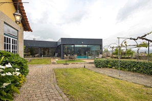 Ein modernes Haus mit Swimmingpool, einer Terrasse mit Gartenmöbeln und einem gepflegten Garten.