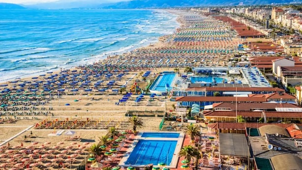 Un hôtel situé sur la côte, doté d’une plage, d’une piscine et offrant une vue sur les montagnes à proximité.