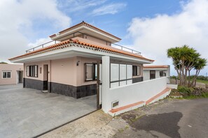 Una casa moderna de dos pisos con techo plano, ventanas amplias y entrada pavimentada.