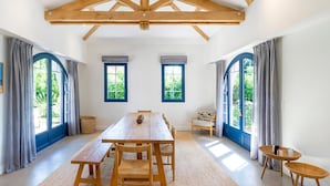 A spacious room with a wooden dining table, benches, and a large window with a view of greenery. - Iparra Holiday Home – Hossegor Golf – 12 Guests, Private Pool, A/C, Near the Beach (Soorts-Hossegor)