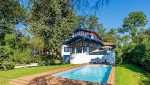 A modern house with a swimming pool, surrounded by lush greenery. - Iparra Holiday Home – Hossegor Golf – 12 Guests, Private Pool, A/C, Near the Beach (Soorts-Hossegor)