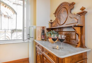 A wooden cabinet with a marble countertop, a wine bottle, and two wine glasses.