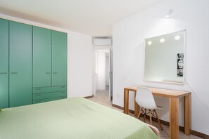 Un dormitorio con cama, escritorio, silla y armario.