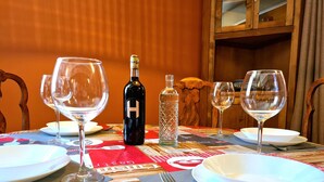 A dining table set with plates, glasses, cutlery, a bottle, and a decorative bottle. - Apartment 'Federico - In Pieno Centro' with Wi-Fi and Air Conditioning (Lucca)