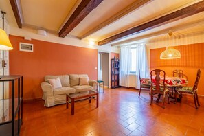 Un soggiorno con divano, tavolino, tavolo da pranzo con sedie e una lampada.