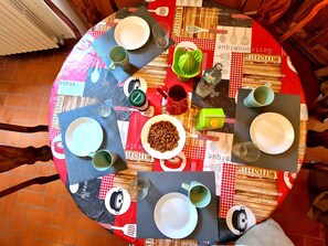 Un tavolo rotondo da pranzo con piatti, tazze e una ciotola di noci.