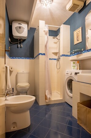 Un bagno con WC, bidet, doccia e lavatrice.