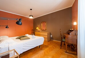 Una camera da letto con un letto, lampade ai comodini, una cassettiera, una scrivania e uno specchio.