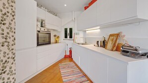 A modern kitchen with white cabinetry, a built-in oven, and a red fire extinguisher.