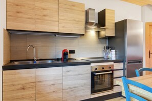 Une cuisine moderne dotée de meubles en bois, d’un réfrigérateur en acier inoxydable et d’un four encastré.