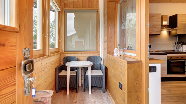 A wooden interior with a dining area, a kitchen, and a window with a view.