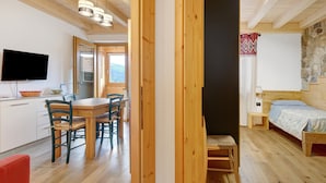 A wooden interior with a dining area, a bed, and a TV.