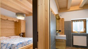 A wooden bedroom with a bed, a nightstand, and a hanging light fixture. - Apartment 'Piano Terra 3' with Mountain View, Private Terrace and Wi-Fi (Romeno)