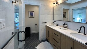 A modern bathroom with a large mirror, two sinks, and a shower area. - Storybook Summer Stay - 4-bedroom house in charming Mill Valley (Mill Valley)