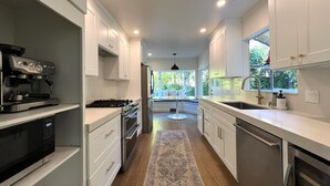 A modern kitchen with white cabinetry, stainless steel appliances, and a central island. - Storybook Summer Stay - 4-bedroom house in charming Mill Valley (Mill Valley)