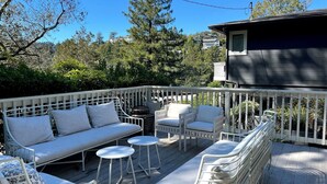 A deck with white outdoor furniture, including a sofa, chairs, and tables. - Storybook Summer Stay - 4-bedroom house in charming Mill Valley (Mill Valley)
