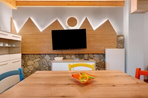 Une cuisine moderne avec un téléviseur à écran plat fixé à un mur en bois, des éléments décoratifs en pierre et une table à manger avec des chaises.
