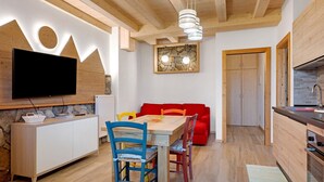 Una cocina moderna con armarios de madera, estufa empotrada y un comedor con mesa de madera y sillas coloridas.