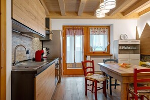 Une cuisine dotée de meubles en bois, d’un évier en acier inoxydable et d’un coin repas avec une table et des chaises en bois.