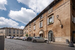 Una calle adoquinada con coches aparcados y un edificio con ventanas de arco y una puerta.