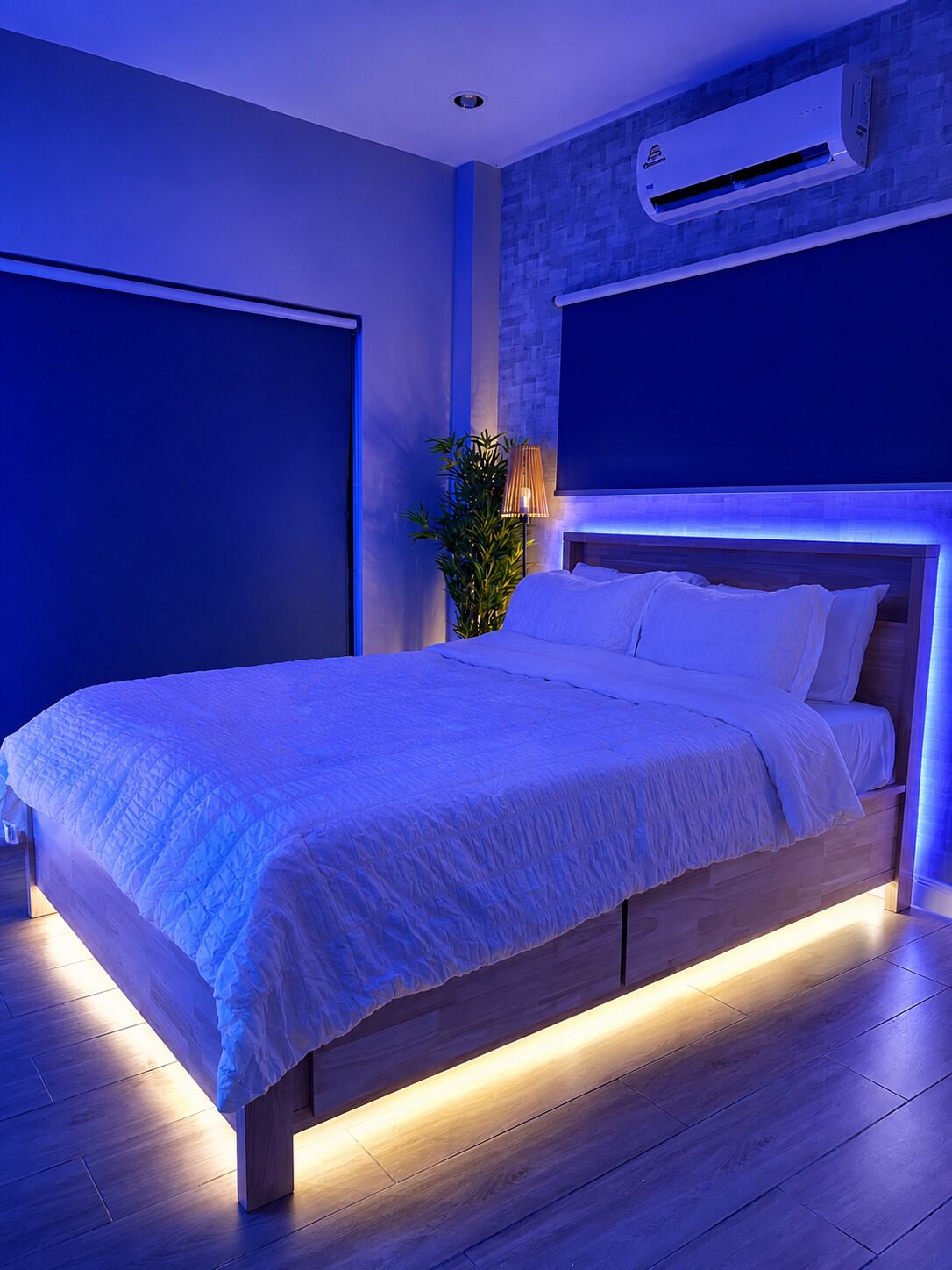 Ein modernes Schlafzimmer mit einem großen Bett, einer Wand-Klimaanlage und einer Topfpflanze.