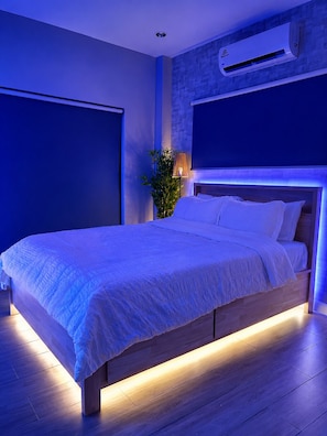 A modern bedroom with a large bed, a wall-mounted air conditioner, and a potted plant.