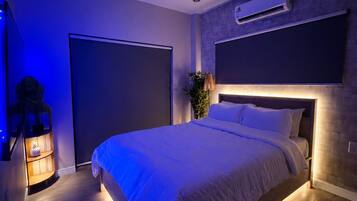 A modern bedroom with a large bed, a wall-mounted air conditioner, and a ceiling light fixture.