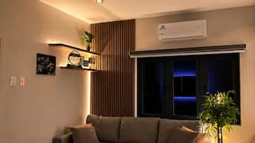Ein modernes Wohnzimmer mit einem Ecksofa, einem Marmortisch, einem Deckenventilator und einer Klimaanlage.