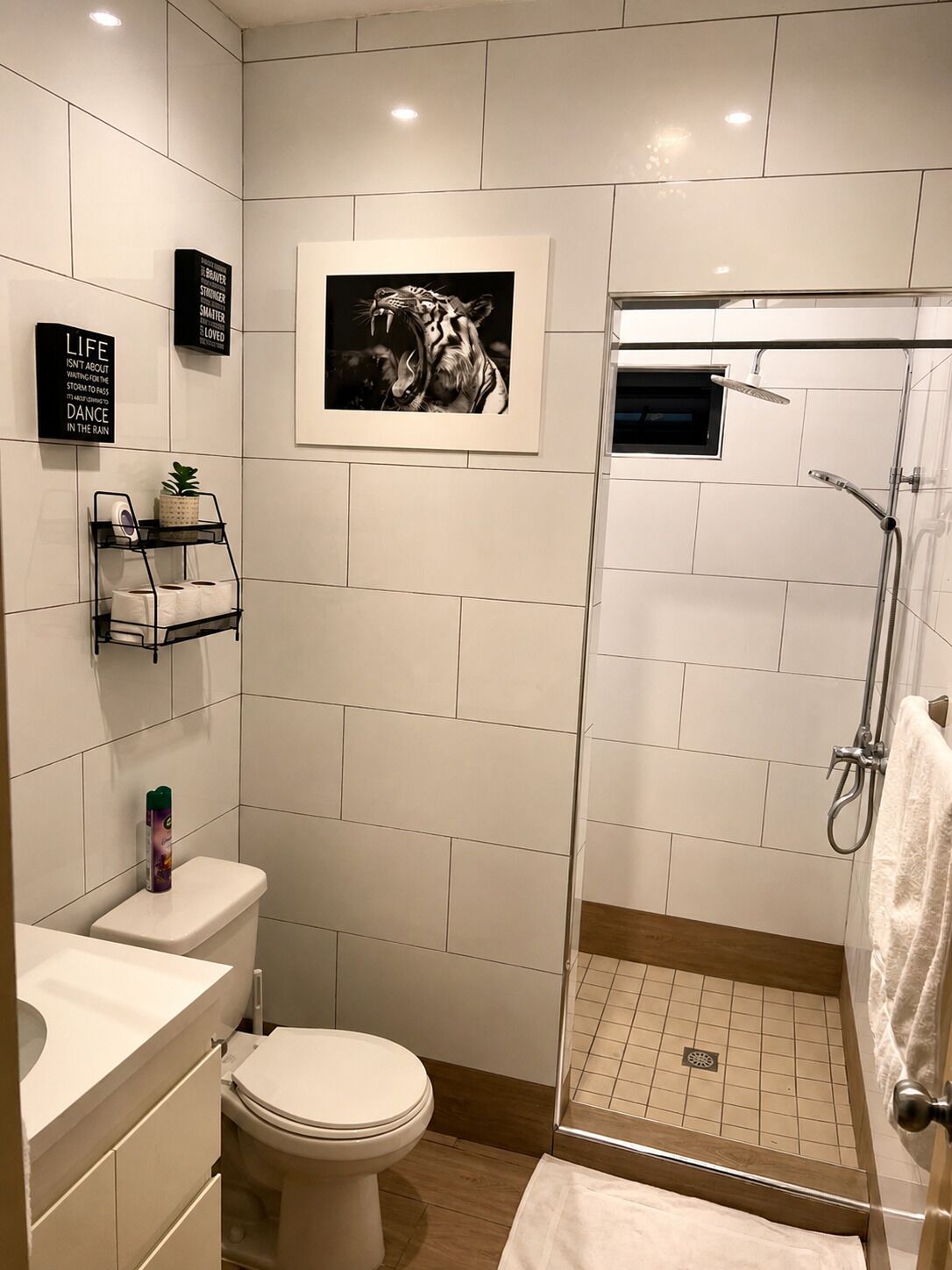 A modern bathroom with a toilet, a shower enclosure, and a framed picture on the wall.