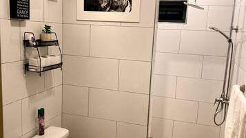 A modern bathroom with a toilet, a shower enclosure, and a framed picture on the wall.
