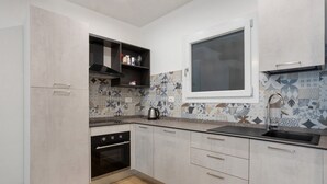 Una cocina moderna con horno empotrado, ventana sobre el fregadero y azulejos decorativos en la pared.