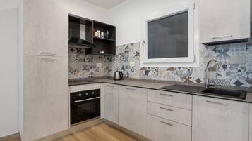 Eine moderne Küche mit Einbauofen, einem Fenster über der Spüle und dekorativen Fliesenspiegeln.
