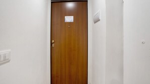 Una puerta de madera con un cartel pequeño, un interruptor de luz y un termostato en la pared.