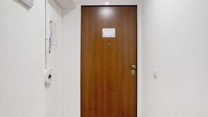 Una puerta de madera con un cartel pequeño, un portero automático y un interruptor de luz.
