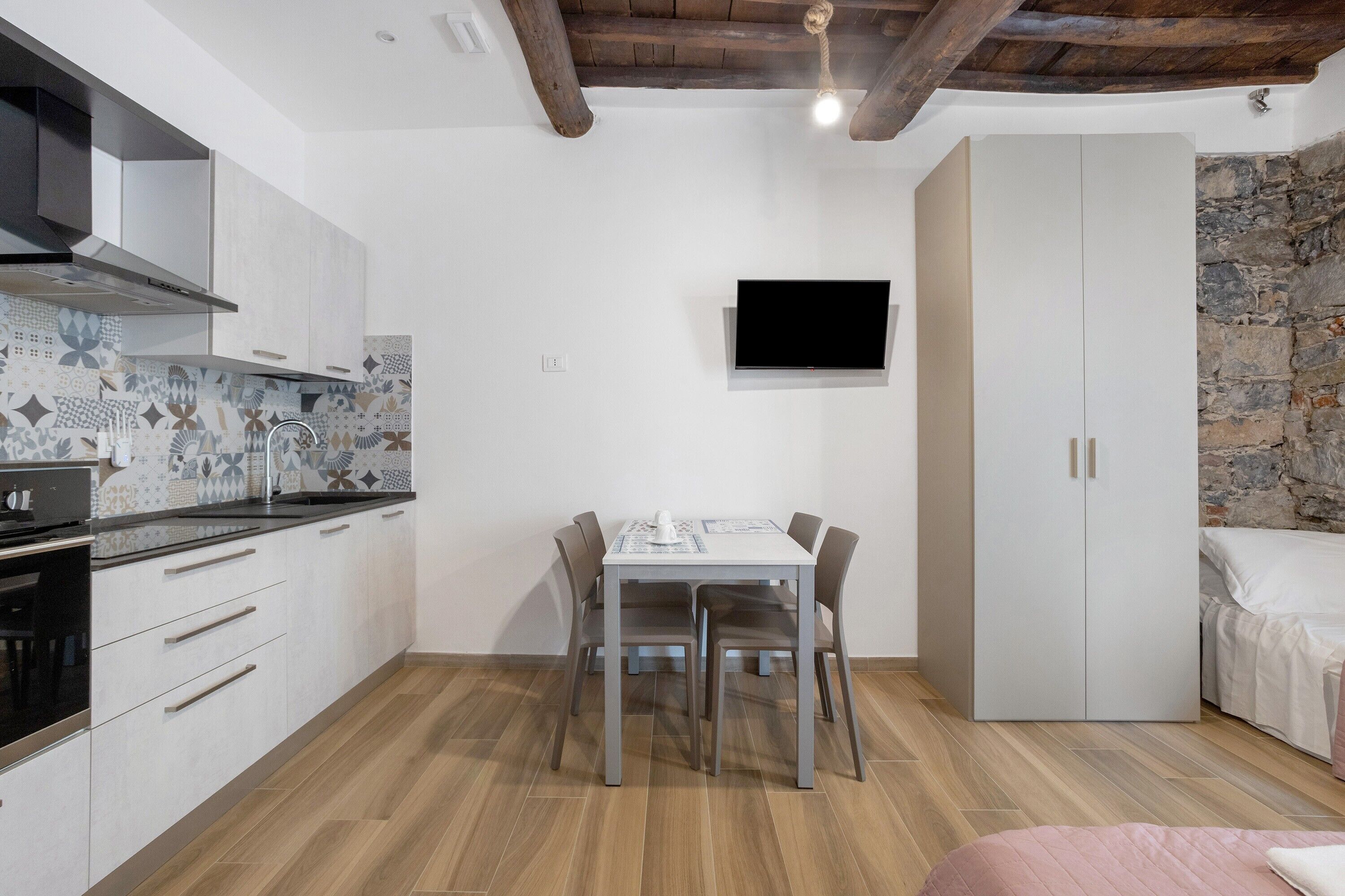Une cuisine compacte comprenant une table à manger, des chaises, un téléviseur et une armoire.