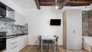 Una cocina compacta con mesa, sillas, televisor y armario.